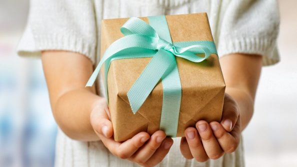 Woman holds wrapped gift in her outstretched hands (model)