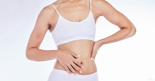 Woman in white lingerie with her hands resting on her waist and stomach (model)