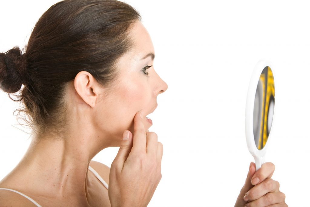 Adult with acne surprised looking in mirror