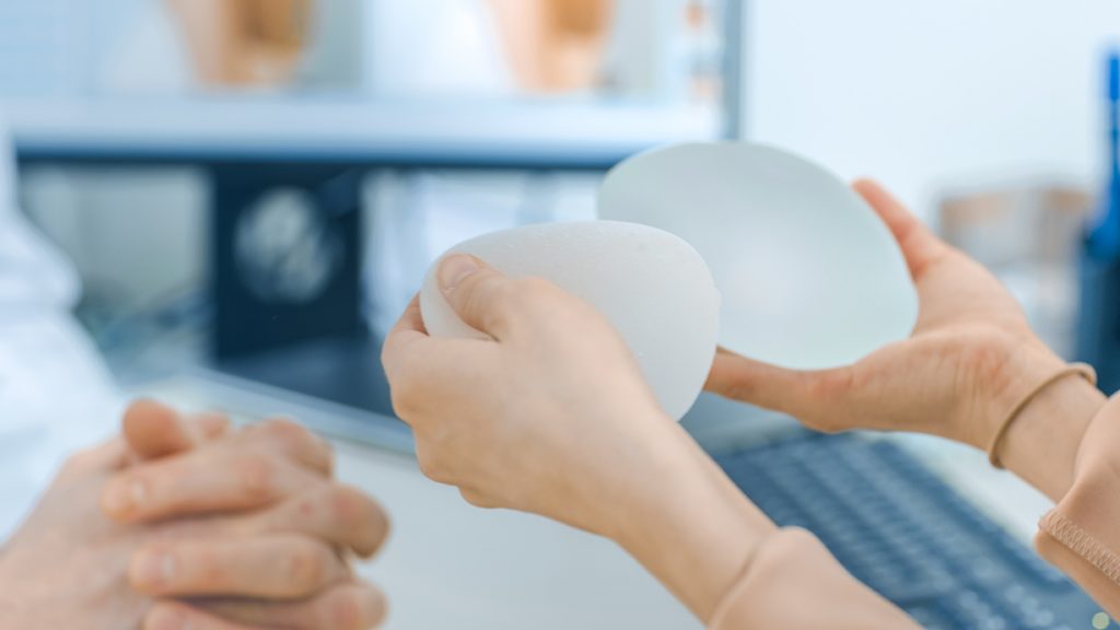 surgeon holding two textured breast implants