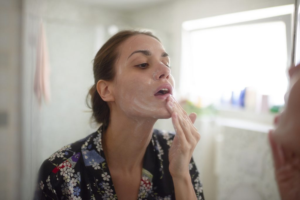 woman applying skincare products to her face