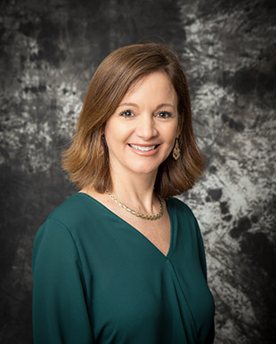 Angela wearing a forest green top and smiling