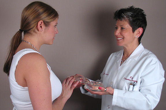 Woman in white lab coat showing patient breast implants
