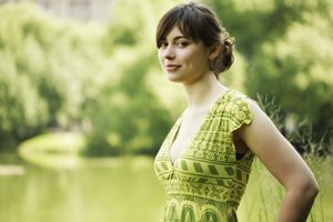 Young woman in a green print dress standing in a green field