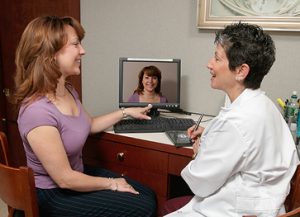 Woman looking at computer screen with imaging technician