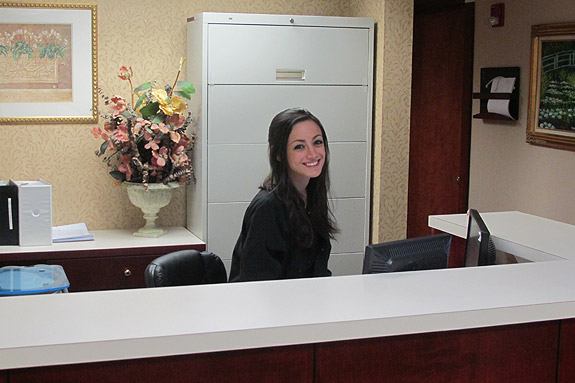 Friendly looking young woman behind the reception desk