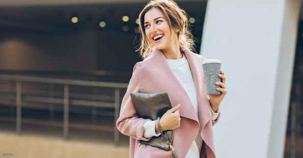 Young woman in pink coat walking on a city street