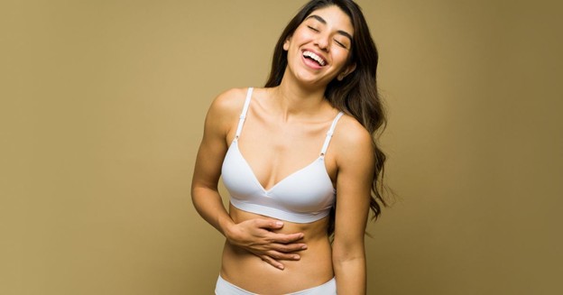 : Laughing woman in white lingerie with her hand on her stomach (model)