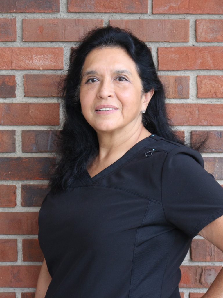 Shoshanna in black scrubs in front of brick wall