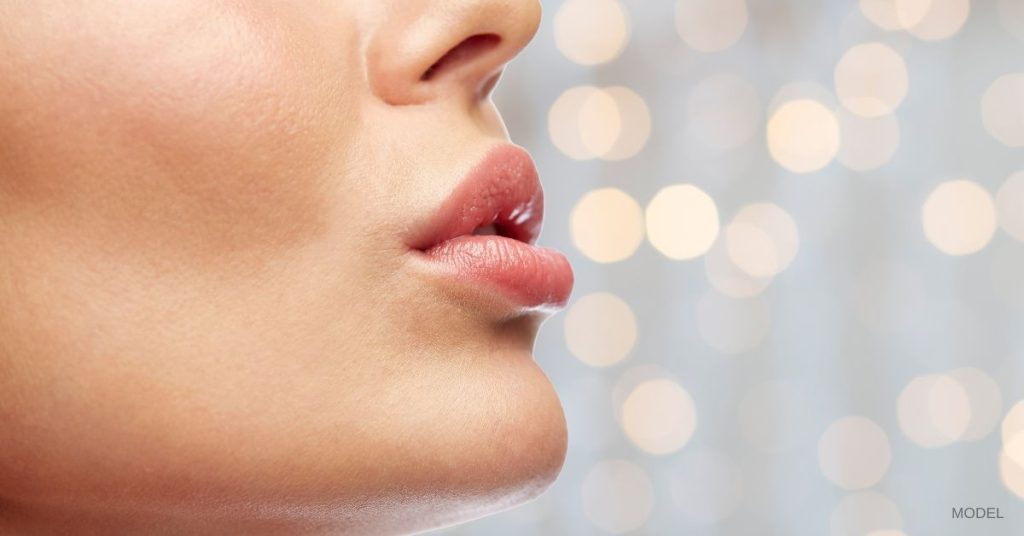 Woman with plump lips (model) against a sparkly white background.