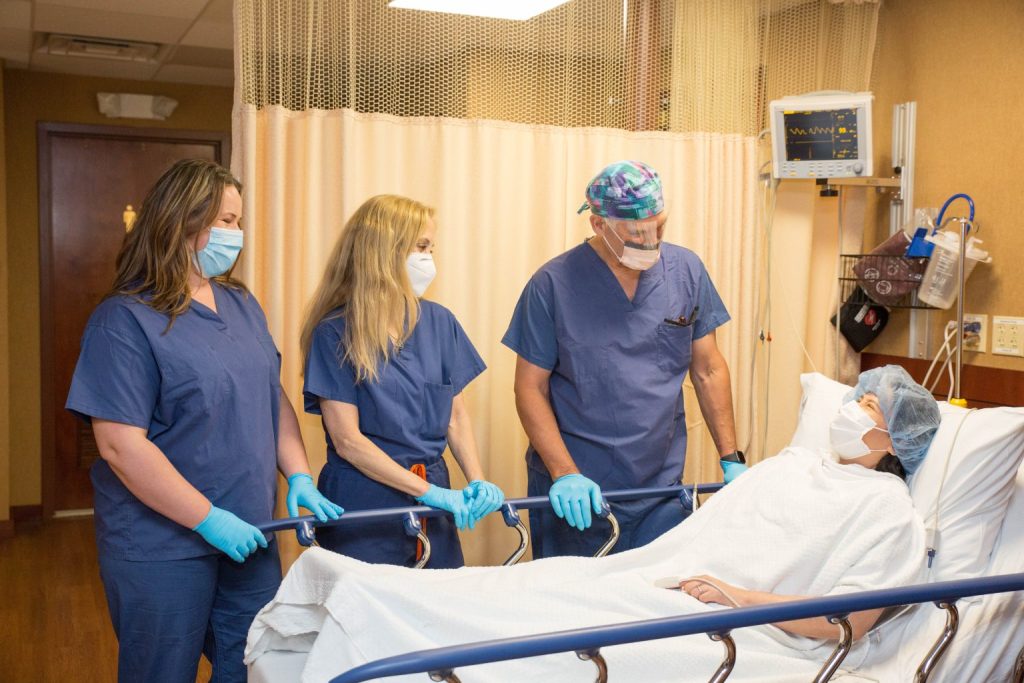 Dr. Parker and 2 staff members in scrubs talking with patient who is ready for the operating room