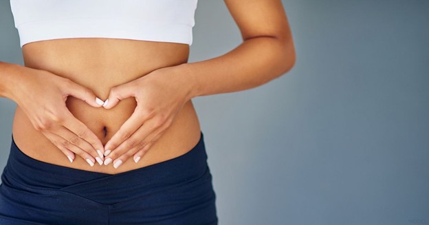 Woman with her hands in the shape of a heart on her stomach (model)