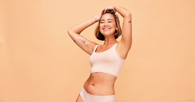 Smiling woman in beige lingerie with her hands over her head (model) 